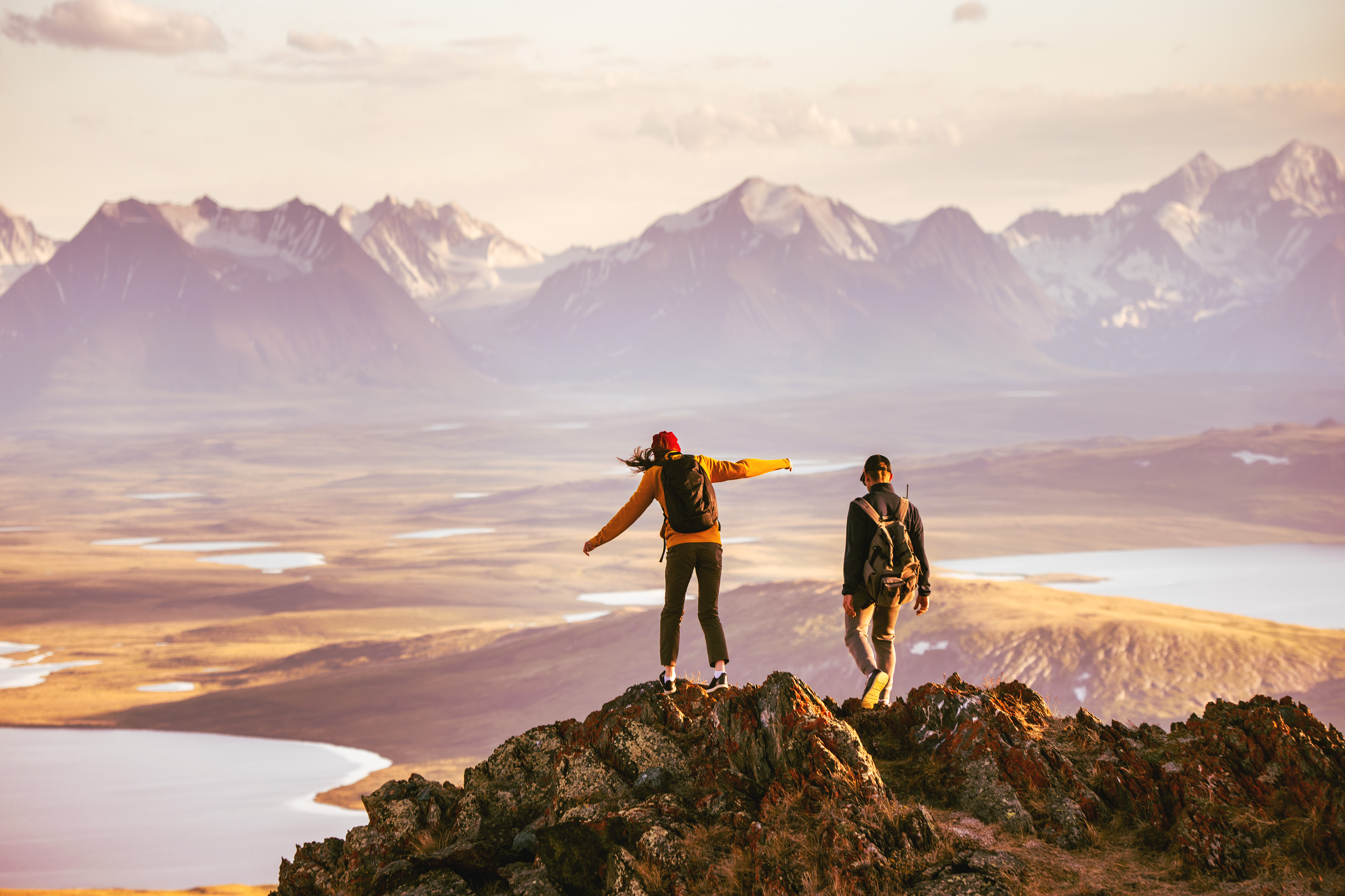 Wanderpaar mit Rucksäcken auf einem Berggipfel mit weitem Ausblick